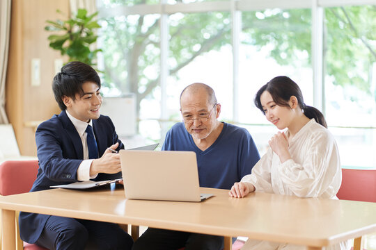 パソコン画面を見ならが説明を受ける高齢者