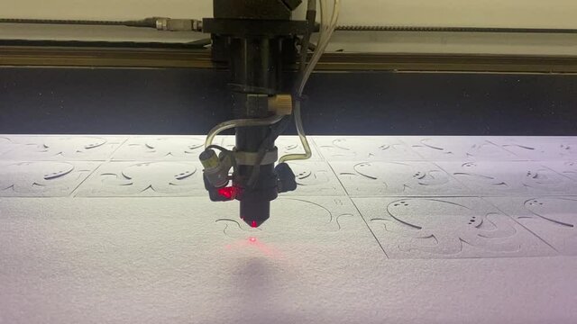 The laser machine at the production site cuts out parts from soft felt with a red laser