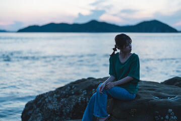 Fototapeta premium 夕暮れの海にいる女性