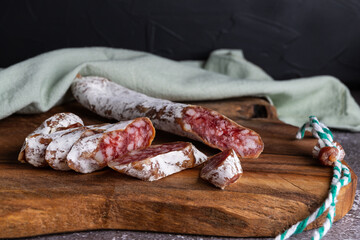 Italian sausage snack. Delicious dry sausage, close-up on a wooden board.