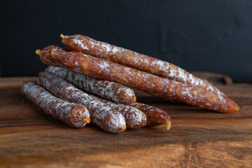 Italian sausage snack. Delicious dry sausage, close-up on a wooden board.