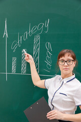 a young woman business coach in a white blouse and glasses shows with her hand a diagram of building a business on a graph. office work