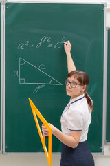 school teacher young woman in the class at the blackboard draws a triangle with a ruler. portrait. close up