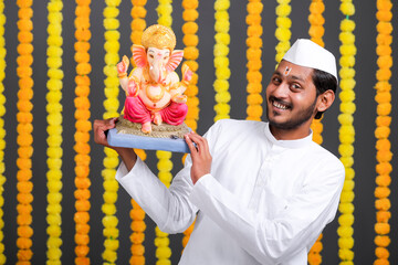 Young indian man with lord ganesha sclupture. celebrate ganesha festival.