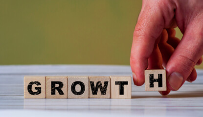 The hand put wooden cube block and creates word GROWTH. Increase business concept