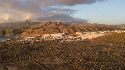 Aerial view of mountains and marine coast, village of houses, dry terrain and trails, Canary Islands