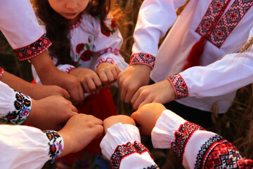 The hands of children in embroidered shirts are joined in a welcoming gesture. The united hands...