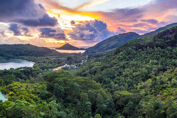 Mahe Island coast drone sunset landscape with dramatic pink sky, clouds, lush tropical forest and...