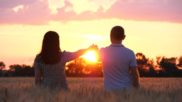 The hands of a man and a woman in the rays of the sun. A happy family holds hands and looks at the sunset. A man and a woman hold hands. Protection and support. Family values