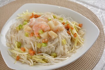 braised wok fried bee hoon vermicelli thin noodle with seafood prawn scallop and vegetables in chef white sauce in white background asian halal menu