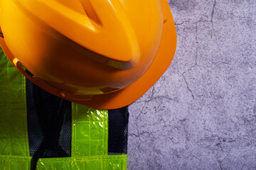 construction helmet and reflective vest on cement backgropund