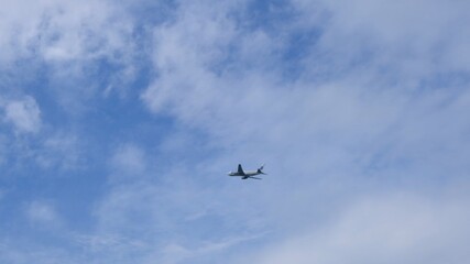 Silhouette Modern large plane flies in the sky. Beautiful blue sky and white clouds in the background. The aircraft flies overhead. Airplane takes off or landing