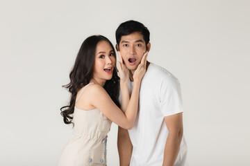 Young attractive Asian couple, man wearing white t shirt and beige pants, woman wearing beige dress. Teasing each other. Concept for pre wedding photography