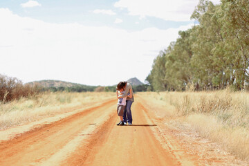 Obraz premium Mother and son standing together in hug on country dirt road