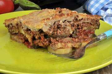 Portion de moussaka servie dans une assiette avec une fourchette en gros plan