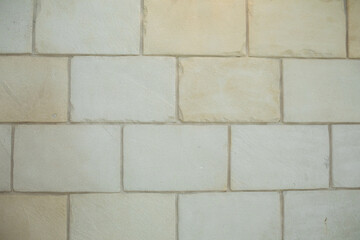 Wall elevation made of sandstone laid in an overlapping brick pattern.
