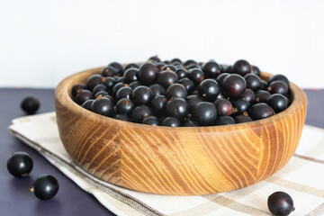 Fresh black currant in wooden bowl on dark table