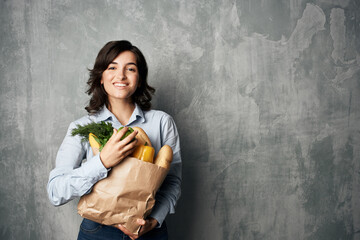 brunette with a package of groceries supermarket vegetables healthy food diet dark background