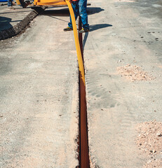 Worker inserts fiber optic cables buried in a micro trench