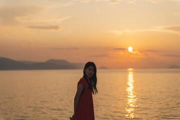Fototapeta premium 夕暮れの海にいる女性