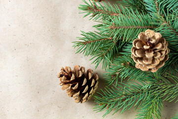 Corner of fir tree branch with cones on craft paper for christmas card with copy space for text. Top view, flat lay