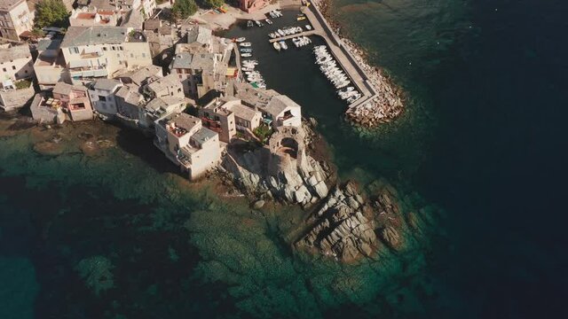 Aerial view of characteristic stone village port in corsica. Vivid blue sea. Aerial view of coast, beautiful sea, houses, trees in a sunny summer day. 