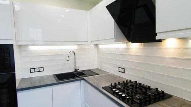 stylish kitchen interior with glossy white cabinets, gas stove and wooden worktop. interior of a small kitchen.