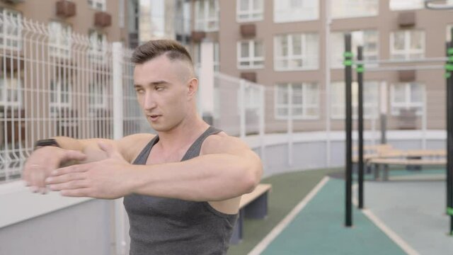 Man is exercising at open air gym. Bodybuilder doing exercises in the open air.