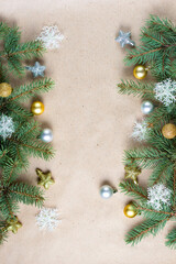 border of fir tree branch with gold decoration on craft paper for christmas card with copy space for text.