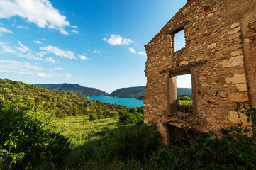 imagen de una casa de piedra derruida en medio de la naturaleza, con un valle de fondo, el cielo azul y las colinas verdes