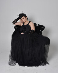 Full length portrait of young  plus sized woman with short  hair,  wearing long black tulle gothic...