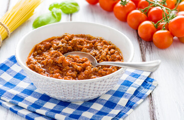 Bowl with ragu sauce on a rustic wooden table.