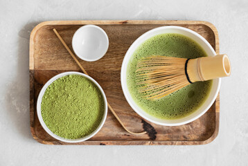 Fototapeta na wymiar Matcha green tea set in a wooden tray. Preparation of matcha tea. Traditional Japanese organic drink. View from above.