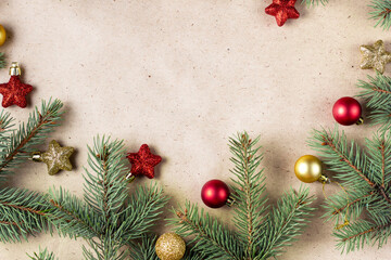 border of fir tree branch with gold and red decoration on craft paper for christmas card with copy space for text.