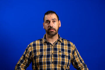 Obraz premium Cheerful emotional man plaid shirt studio lifestyle grimace blue background