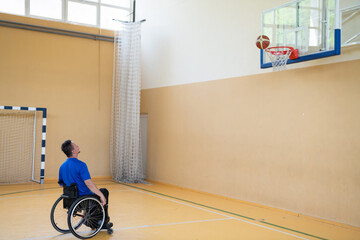 a war invalid in a wheelchair trains with a ball at a basketball club in training with professional...