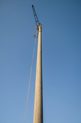 Obraz premium An electrician with equipment climbs an old concrete electricity pole.