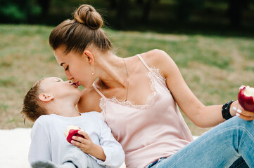 Mom and son eating apples on a blanket on a picnic in the summer. Happy family  in the park on...