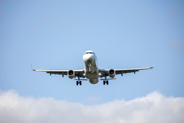 Airplane landing against blue sky and clouds. Airliner approaching an airport.