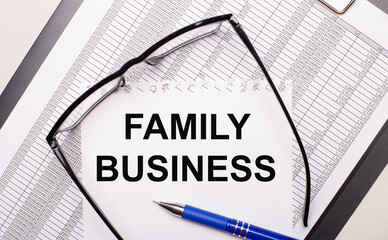 On a light background, a report, black-framed glasses, a pen and a sheet of paper with the text FAMILY BUSINESS. Business concept
