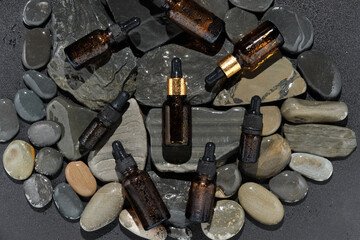 bottle with micellar water, essence of natural oil, serum serum for the face. Some brown glasses bottles with pipette on sandstone stone