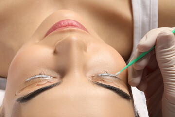 Young woman undergoing eyelash lamination, closeup. Professional service