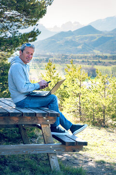 Homme entrepreneur qui travaille avec son ordinateur et son téléphone en pleine nature à la montagne