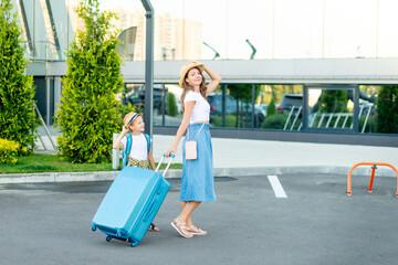 a happy mother with a child with a blue suitcase is going on vacation or a trip and going to the airport