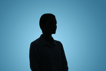 Silhouette of anonymous woman on light blue background