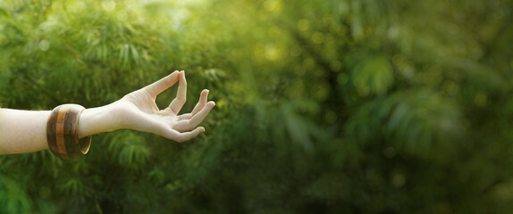 Hand in meditation gyan mudra position in natural environment. Nature meditation banner with copy space.