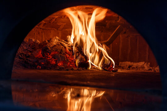 Close up detail of burning wood inside a classic oven to bake italian pizza.