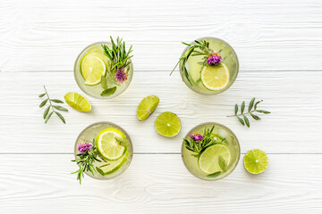 Lemonade with lemon slices and herbs in glasses with lemon reamer