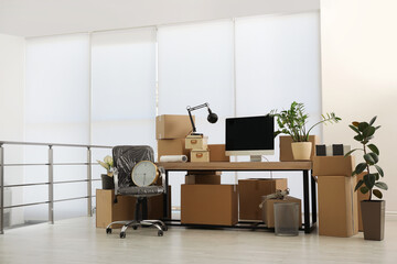 Cardboard boxes, computer and furniture in new office. Moving day