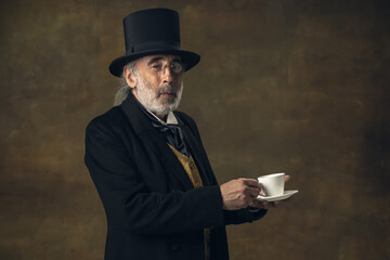 Portrait of elderly gray-haired man, gentleman, aristocrat or actor isolated on dark vintage...